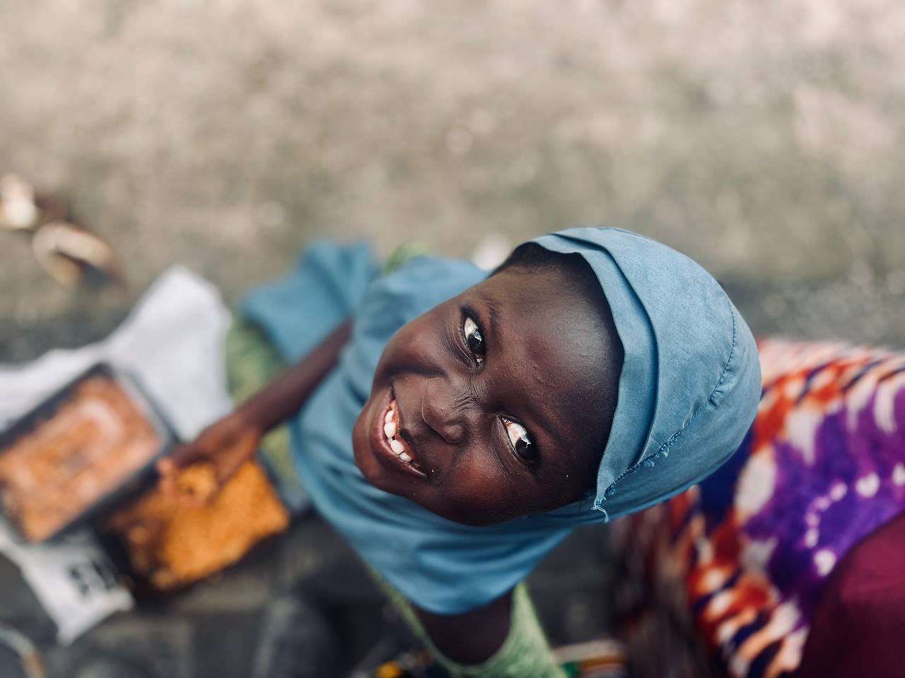 A child smiling, a meal beside her